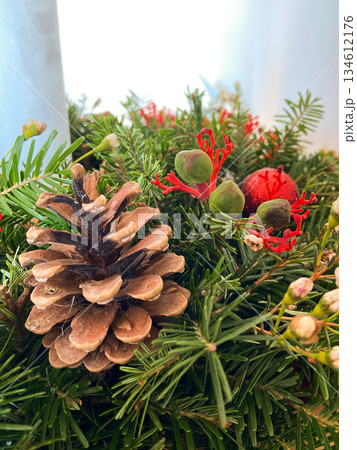 Evergreen branches with pinecone and red berries. Natural holiday decoration, winter symbolism, organic textures and calm seasonal festive atmosphere. Evergreen branches with pinecone and red berries. Natural holiday decoration, winter symbolism, organic textures and calm seasonal festive atmosphere. 134612176