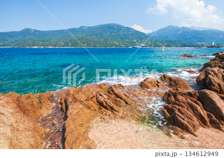 A vivid coastal scene with rugged rocks along a sandy beach and calm turquoise water A vivid coastal scene with rugged rocks along a sandy beach and calm turquoise water 134612949