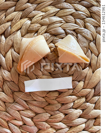 Fortune cookies placed on woven straw surface with blank message strip. Symbolic food styling, anticipation, curiosity and minimalist still life composition Fortune cookies placed on woven straw surface with blank message strip. Symbolic food styling, anticipation, curiosity and minimalist still life composition 134612961