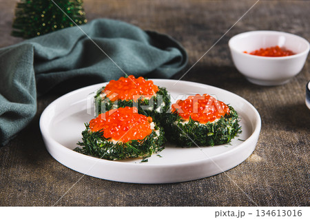 Original small sandwiches with butter and red caviar on a plate on the table Original small sandwiches with butter and red caviar on a plate on the table 134613016