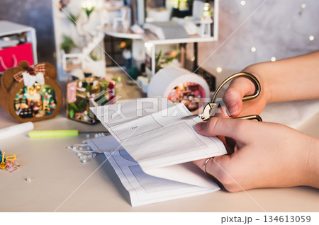 A girl cuts out a paper piece for a roombox pattern 134613059