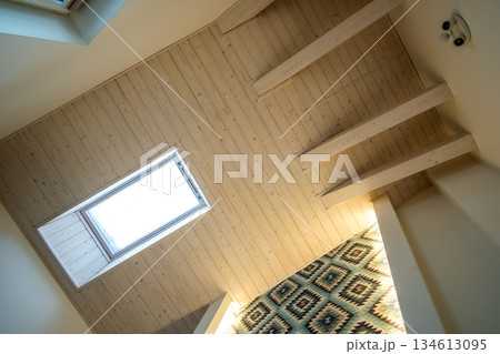 Wooden ceiling in a contemporary mansard room with attic window ob decorative planks surface. 134613095