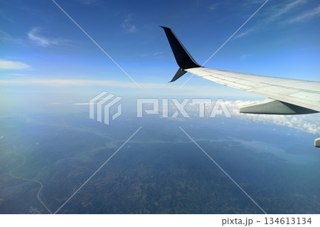 View through airplane window of commercial jet plane wing flying high in the sky. Air travelling concept View through airplane window of commercial jet plane wing flying high in the sky. Air travelling concept 134613134
