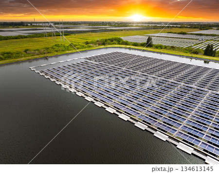View from above of floating photovoltaic power plant with many rows of solar panels for producing clean electrical energy. Concept of renewable electricity on water surface with no air pollution View from above of floating photovoltaic power plant with many rows of solar panels for producing clean electrical energy. Concept of renewable electricity on water surface with no air pollution 134613145