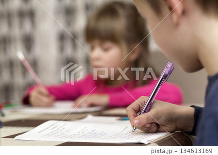 Two cute young children, boy and girl, brother and sister doing homework, writing and drawing at home on blurred background. Art education, creativity and children activities concept. 134613169