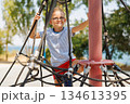 Young Boy Climbing Rope Structure at Outdoor Playground 134613395