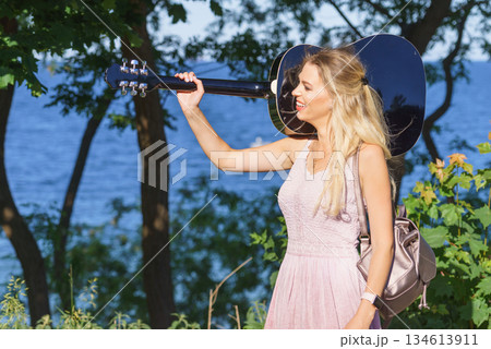 Woman playing acoustic guitar in park Woman playing acoustic guitar in park 134613911