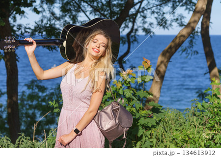Woman playing acoustic guitar in park 134613912