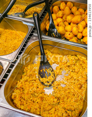 Colorful hot buffet trays with spiced rice, curry sauce, and seasoned potatoes in cafeteria Colorful hot buffet trays with spiced rice, curry sauce, and seasoned potatoes in cafeteria 134613950