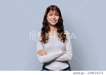 Portrait of smiling confident teenage girl with crossed arms on light background 134614171