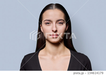 Portrait of beautiful smiling young woman against gray studio background 134614179