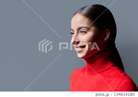 Profile portrait of young smiling woman on gray background Profile portrait of young smiling woman on gray background 134614180
