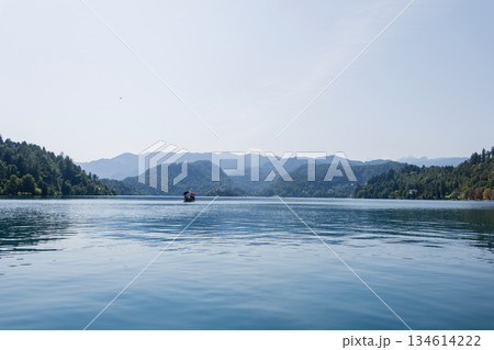 Beautiful Lake Bled in Slovenia with tranquil water, lush green hills, and mountains in the background under a bright clear sky. Old church on the island 134614222