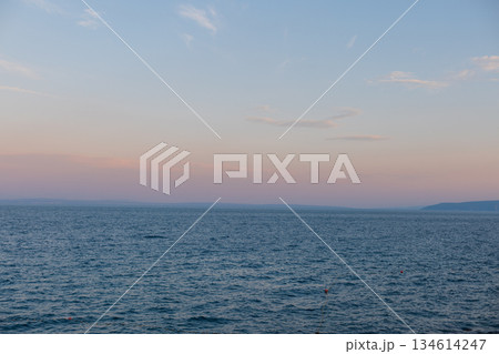 Evening by the sea. Blue ocean surface with calm waves fading into the horizon. Natural seascape symbolizing freedom, calmness, and serenity. Beautiful sea view with mountains after sunset. Holidays 134614247