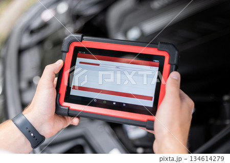 Modern auto diagnostic tool in hands of mechanic inside car, testing vehicle systems and detecting possible faults. Car service and maintenance. 134614279