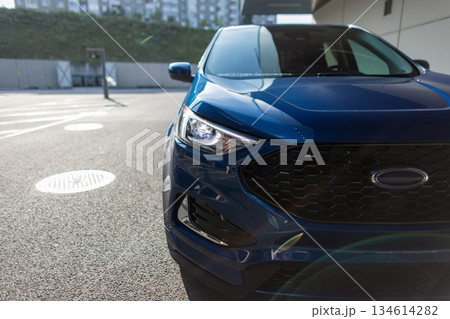 Luxury urban vehicle parked near high-rise building, blue SUV front exterior detail. Luxury urban vehicle parked near high-rise building, blue SUV front exterior detail. 134614282