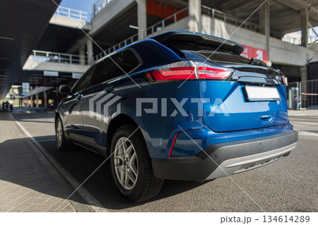 Blue modern SUV parked outdoors near urban architecture, rear view with sleek tail lights and stylish design, representing contemporary transportation and city lifestyle. Blue modern SUV parked outdoors near urban architecture, rear view with sleek tail lights and stylish design, representing contemporary transportation and city lifestyle. 134614289
