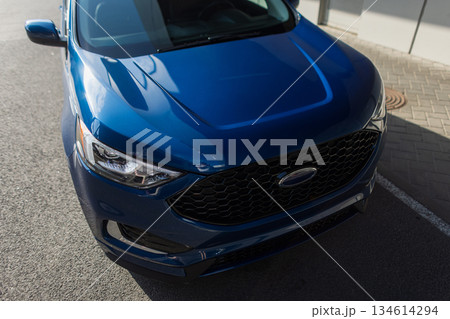 Modern blue SUV parked on city street with sunlight reflections on shiny surface and contemporary design details. Modern blue SUV parked on city street with sunlight reflections on shiny surface and contemporary design details. 134614294