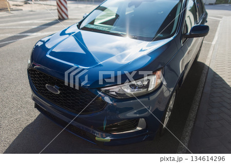 New modern SUV in blue color standing outdoors near road and buildings in daylight. 134614296