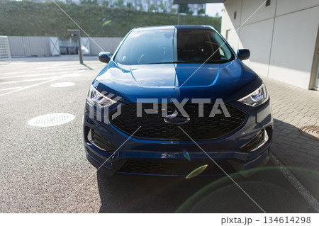 Urban transportation concept with parked automobile, shining headlights, and city background. Blue SUV automobile parked outdoors, stylish rear view shot. Urban transportation concept with parked automobile, shining headlights, and city background. Blue SUV automobile parked outdoors, stylish rear view shot. 134614298