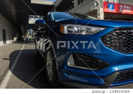 Automobile parked in modern city environment with focus on stylish vehicle details. Blue automobile side profile view parked near concrete industrial wall. Automobile parked in modern city environment with focus on stylish vehicle details. Blue automobile side profile view parked near concrete industrial wall. 134614304