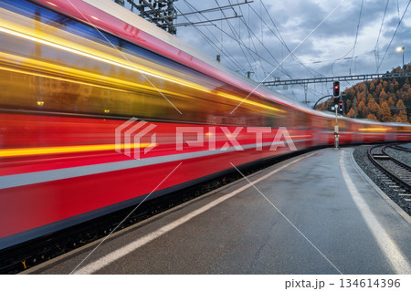 Blurred red passenger train passing mountain railway station 134614396
