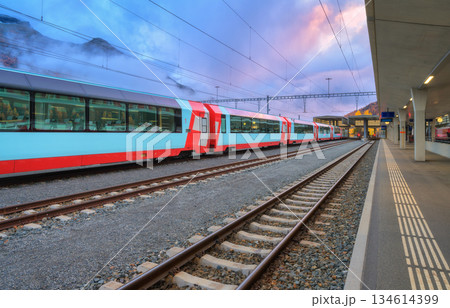 Red and blue modern passenger train standing at railway station Red and blue modern passenger train standing at railway station 134614399