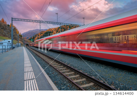 Blurred red passenger train passing mountain railway station 134614400