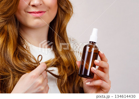 Woman applying hair cosmetic Woman applying hair cosmetic 134614430