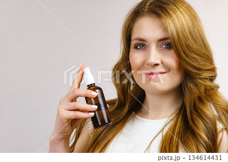Woman applying hair cosmetic Woman applying hair cosmetic 134614431