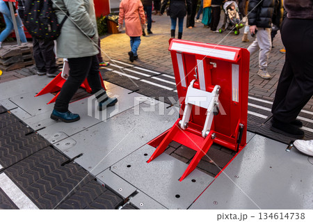 Red retractable security barrier install pedestrian zone Christmas market Europe walking visitors festive urban atmosphere. Public safety infrastructure protect crowd holiday event city street access 134614738