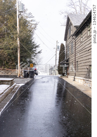 A street is covered in snow and has a few cars parked on it A street is covered in snow and has a few cars parked on it 134614757