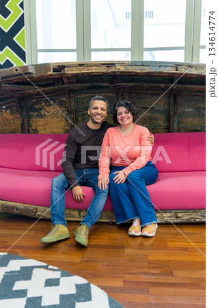 A man and a woman are sitting on a pink couch 134614774