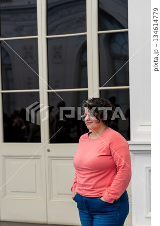 A woman in a pink sweater stands in front of a white door A woman in a pink sweater stands in front of a white door 134614779
