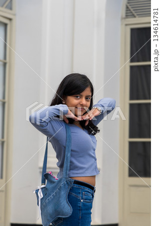 A teen wearing a blue shirt and jeans is holding a blue bag A teen wearing a blue shirt and jeans is holding a blue bag 134614781