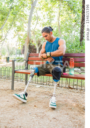 Disabled athlete checking smartwatch while resting during outdoor training 134615396