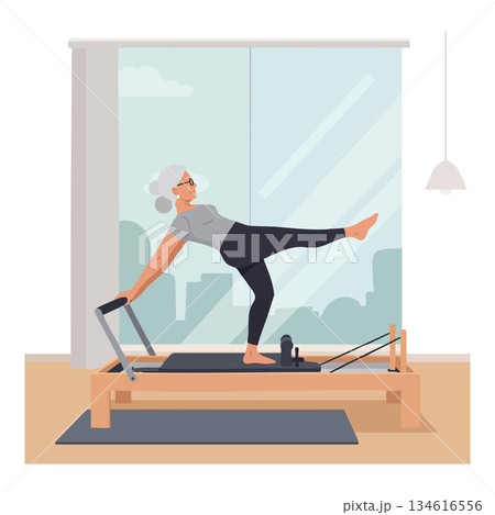 Senior woman practicing pilates reformer exercise at home with city view window 134616556