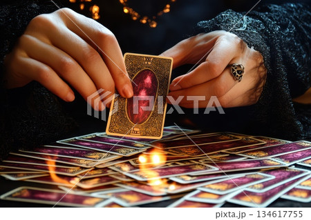 Mysterious fortune teller with piercing eyes and tarot cards on dark surface 134617755