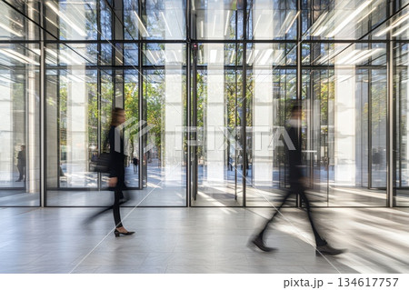 Professional individuals in dark suits walking through a modern business setting 134617757