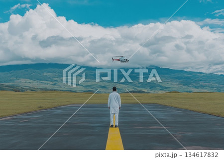 Individual in White Coat Standing on Runway with Helicopter in Background Under Clouds 134617832