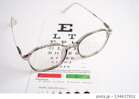 Glasses on eye testing exam chart to check eyesight accuracy of reading. Glasses on eye testing exam chart to check eyesight accuracy of reading. 134617912