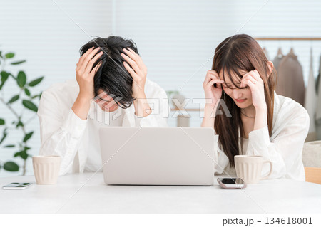 自宅のリビングでパソコンを見ながらショックを受ける若い夫婦,カップル 自宅のリビングでパソコンを見ながらショックを受ける若い夫婦,カップル 134618001
