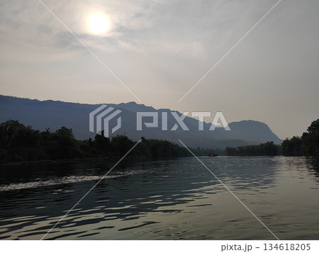 Peaceful river landscape with mountain range silhouette under the hazy sun 134618205