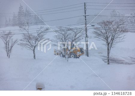 早朝の大雪の中で作業する除雪車と道路 134618728