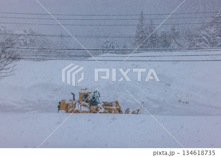 早朝の大雪の中で作業する除雪車と道路 134618735
