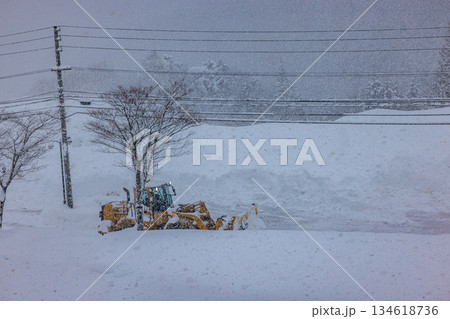 早朝の大雪の中で作業する除雪車と道路 134618736