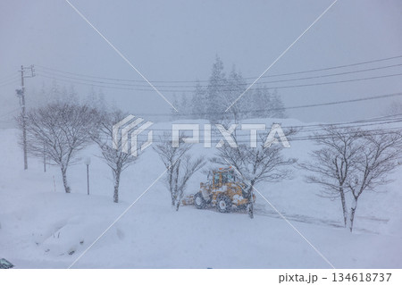 早朝の大雪の中で作業する除雪車と道路 134618737
