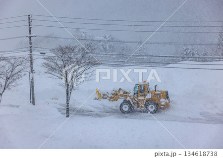 早朝の大雪の中で作業する除雪車と道路 134618738