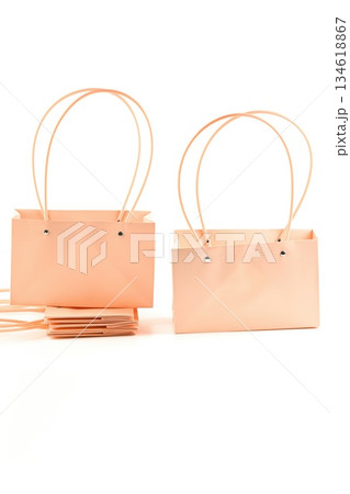Peach pastel paper flower bags with handles on white background. Empty floral packaging for bouquets used in flower shops and retail display. 134618867