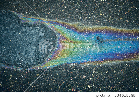 Oil Slick Covering a Section of Asphalt, Creating a Rainbow Effect Under Natural Light 134619389